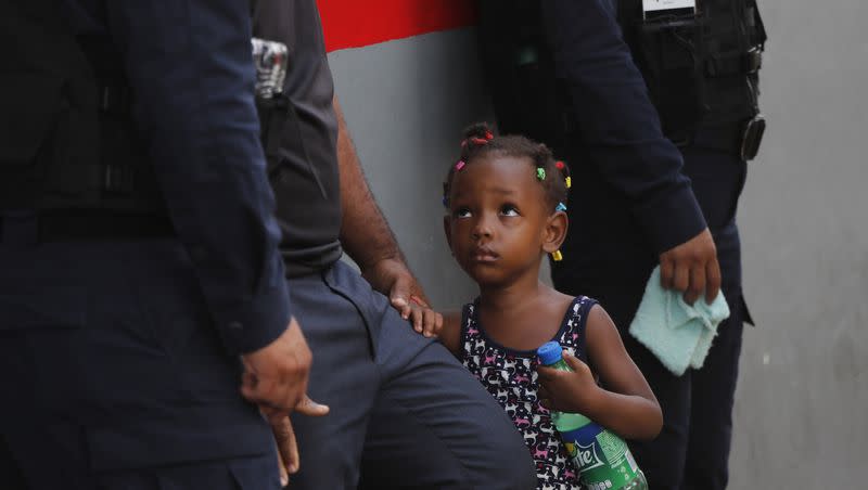 In this May 27, 2019, photo, federal police and migration officers hold a child after her mother tried to jump the line at an immigration center in Tapachula, Chiapas state, Mexico.
