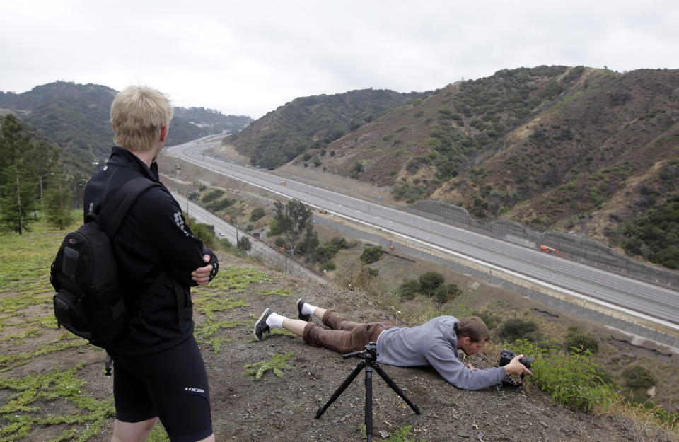 Ian Kalmbaugh, lying on the ground, photographs Interstate 405 as a 10-mile stretch of the freeway is shut down to demolish the Mulholland Drive bridge in Los Angeles, Saturday, July 16, 2011. Traffic in the Los Angeles area is so far moving smoothly, several hours after authorities shut down the 10-mile (16-kilometer) stretch of one of the busiest U.S. freeways for a massive 53-hour construction project. (AP Photo/Jae C. Hong)