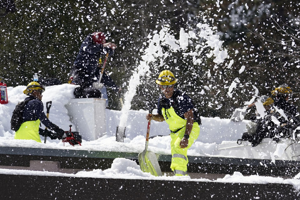 Members of a Cal Fire crew clear snow off the roof of the town's post office after a series of storms Wednesday, March 8, 2023, in Crestline, Calif. Residents of Southern California mountain towns are still struggling to dig out and get necessities in the aftermath of a record-setting blizzard last month that dumped so much snow that roads became impassable and roofs collapsed. (AP Photo/Marcio Jose Sanchez)