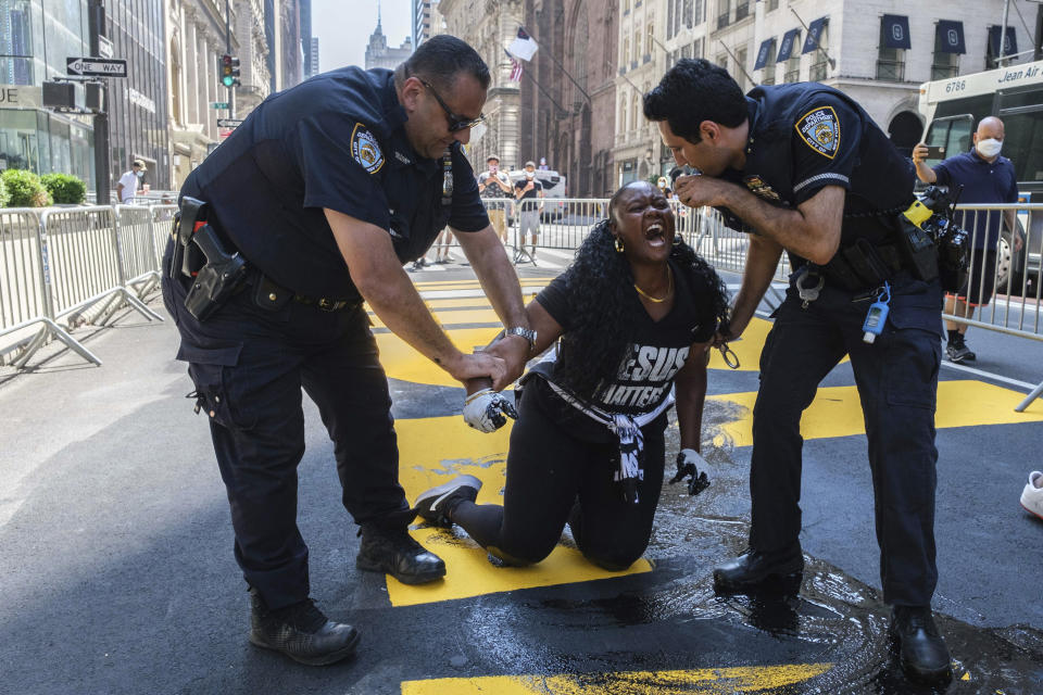 New York Police Department officers attempt to detain a protester who defaced with black paint the Black Lives Matter mural outside of Trump Tower on Fifth Avenue Saturday, July 18, 2020, in the Manhattan borough of New York. The “Black Lives Matter” street mural in front of Manhattan’s Trump Tower has been defaced with paint for the third time in a week. (AP Photo/Yuki Iwamura)
