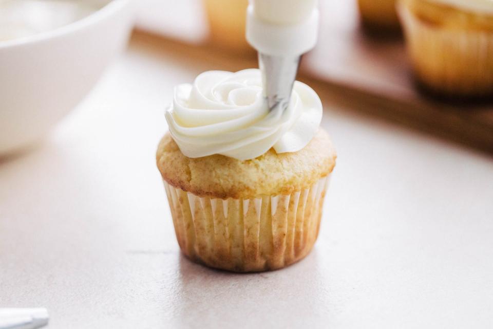 piping frosting onto a cupcake