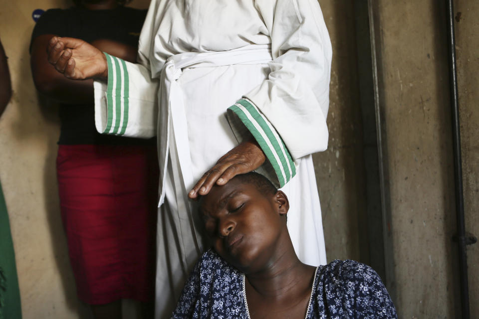 Esther Zinyoro Gwena comforts a woman in labor, in her tiny apartment in the poor suburb of Mbare in Harare, Zimbabwe in this Saturday, Nov, 16, 2019. 72-year old grandmother Esther Zinyoro Gwena claims to be guided by the holy spirit and has become a local hero, as the country’s economic crisis forces closure of medical facilities, and mothers-to-be seek out untrained birth attendants.(AP Photo/Tsvangirayi Mukwazhi)