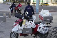 Delivery men prepare to deliver their orders for a supermarket in Beijing, Friday, Nov. 25, 2022. Residents of China's capital were emptying supermarket shelves and overwhelming delivery apps Friday as the city government ordered accelerated construction of COVID-19 quarantine centers and field hospitals. (AP Photo/Ng Han Guan)