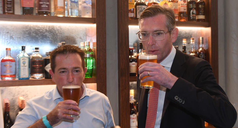 NSW Premier Dominic Perrottet and NSW Deputy Premier Paul Toole drinking a beer standing up, despite it being against public health orders. Source: AAP 