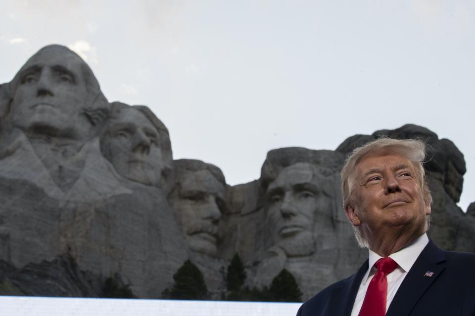 <span class="caption">Sur cette photo datant de juillet 2020, l'ancien président Donald Trump se tient devant une image du Mont Rushmore, dans le Dakota du Sud, où ont été sculptés dans la pierre les visages des présidents Theodore Roosevelt, Thomas Jefferson, George Washington et Abraham Lincoln. </span> <span class="attribution"><span class="source">Photo AP/Alex Brandon</span></span>