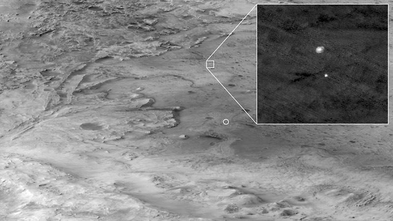 Perseverance's landing in Jezero Crater was timed to coincide with a fly over by NASA's Mars Reconnaissance Orbiter spacecraft, which relayed telemetry from the rover back to Earth. The orbiter also snapped this photo showing Perseverance's fully inflated parachute, connected to the rover's protective aeroshell, descending toward the landing site. The small circle indicates the rover's landing site. The MRO spacecraft was 435 miles from Perseverance and traveling through space at 6,750 mph when this photo was taken. / Credit: NASA/JPL-Caltech/University of Arizona