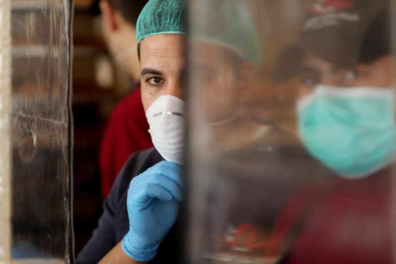 Palestinians, wearing masks as a preventive measure against the coronavirus disease, work in a bakery in Gaza City