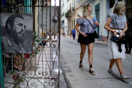 Tourists walk past an image of Cuba's late president Fidel Castro in downtown Havana, Cuba, November 11, 2017. Picture taken on November 11, 2017. REUTERS/Alexandre Meneghini