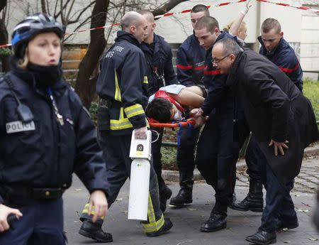 Firefighters carry a victim on a stretcher at the scene after a shooting at the Paris offices of Charlie Hebdo, January 7, 2015. REUTERS/Jacky Naegelen