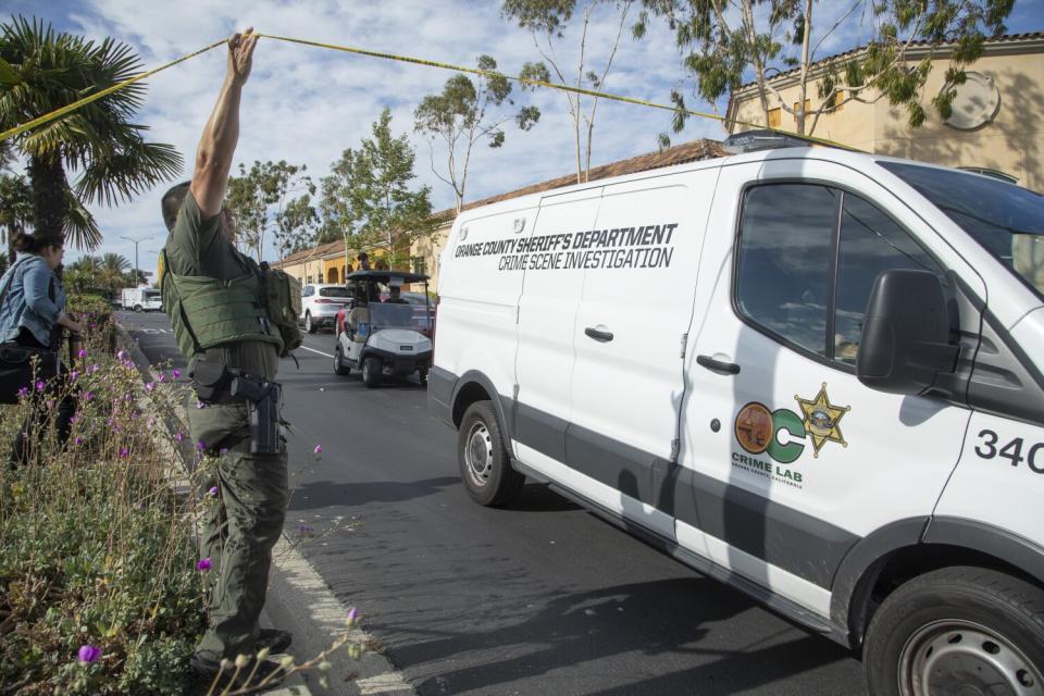 A sheriff's vehicle driving past yellow police tape