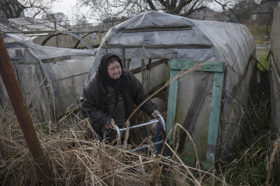 Olga Lehan, 71, walks in a yard of her house in the village of Demydiv, about 40 kilometers (24 miles) north of Kyiv, Ukraine, Tuesday, Nov. 2, 2022. Olga Lehan's home near the Irpin River was flooded when Ukraine destroyed a dam to prevent Russian forces from storming the capital of Kyiv just days into the war. Weeks later, the water from her tap turned brown from pollution. (AP Photo/Andrew Kravchenko)
