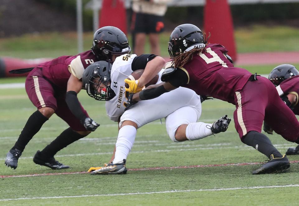 Saint Anthony's Timmy Longo (12) is tackled by Iona's Jaden Codrington (2) and Adande Nartey (4) after a catch and run during CHSAA football action at Iona Prep in New Rochelle Oct. 1, 2022. Saint Anthony's won the game 48-42.