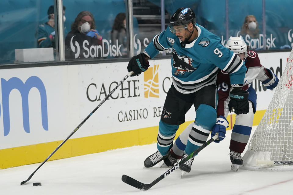 San Jose Sharks left wing Evander Kane (9) reaches for the puck in front of Colorado Avalanche defenseman Samuel Girard during the second period of an NHL hockey game in San Jose, Calif., Monday, March 1, 2021. (AP Photo/Jeff Chiu)