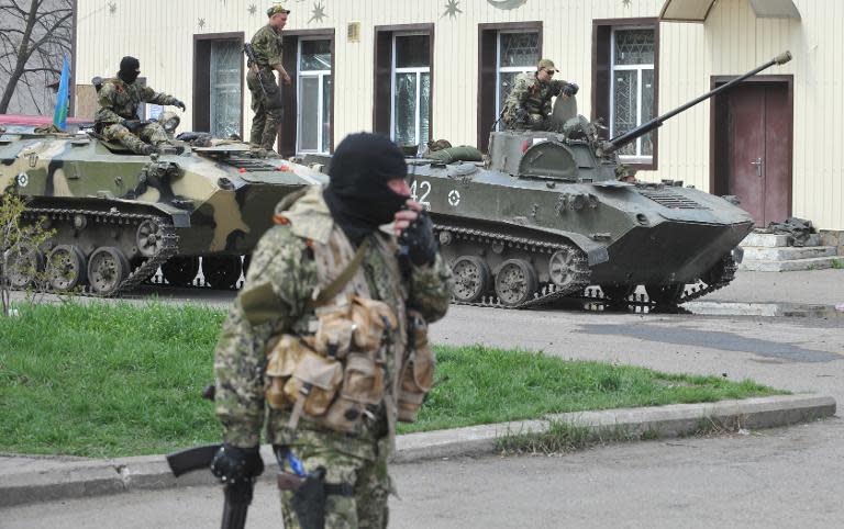 Armed men wearing military fatigues gather around military vehicles as they stand guard outside the regional state building in the eastern Ukrainian city of Slavyansk, on April 16, 2014