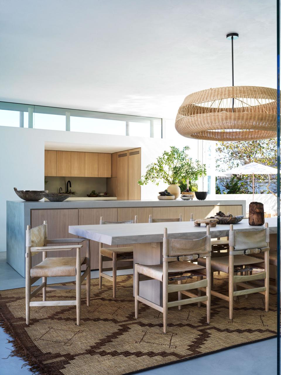 For a Bohemian nod, Alexander mixed vintage pieces with new, custom furniture in a pale, sun-bleached palette. A custom live-edge white oak slab dining table by Alexander Design is surrounded by Stahl + Band custom undyed hide and white oak Campaign chairs. The wicker pendant is by Atelier Vime while the vintage rug is from Garde.