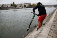 An employee of bicycle sharing service Lime fishes an abandoned electric scooter Lime-S out of the River Seine in Paris