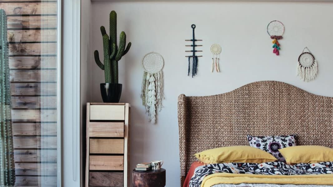  A bedroom with a cactus placed atop a nightstand. 