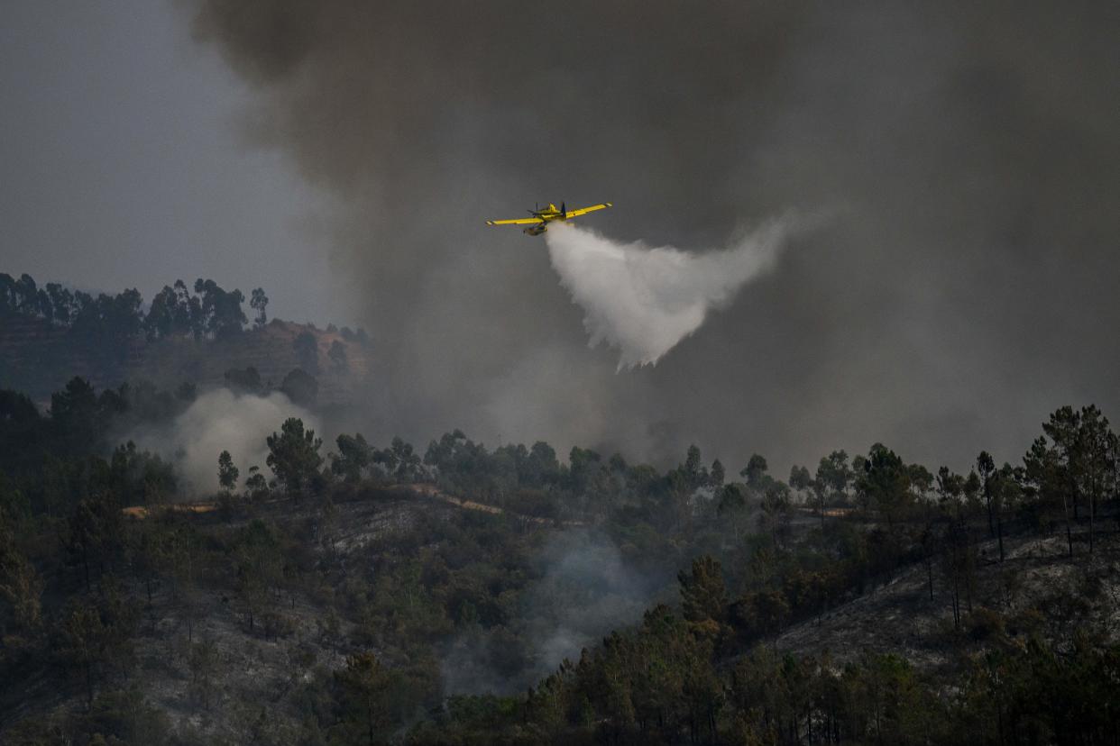 TOPSHOT - A firefighter plane drops water over a wildfire in Odeceixe, south of Portugal, on August 8, 2023. Hundreds of firefighters were today battling a wildfire that has burned for four days in Portugal, which, like neighbouring Spain, is sweltering in a heatwave that has triggered widespread weather alerts. The Iberian Peninsula is bearing the brunt of climate change in Europe, witnessing increasingly intense heatwaves, droughts and wildfires. (Photo by Patricia DE MELO MOREIRA / AFP) (Photo by PATRICIA DE MELO MOREIRA/AFP via Getty Images)