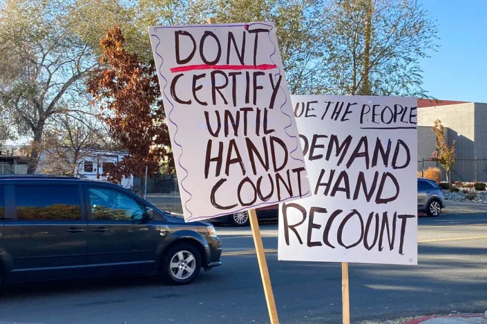 Signs are displayed outside the Washoe County Commission chambers to demand a hand count of ballots before commissioners were scheduled to canvass the vote in Reno, Nev., Friday, Nov. 18, 2022.