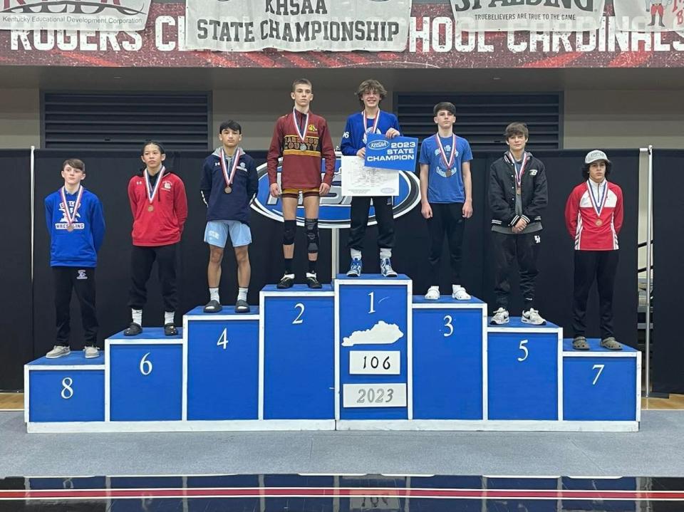 Braydan Blevins of Simon Kenton, center, received his medal for winning the 106-pound weight class in the Kentucky High School Athletic Association state meet Feb. 25, 2023, at George Rogers Clark High School.