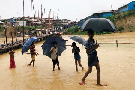 Rohingya refugee children walk along the water as parts of the Kutupalong camp flooded during heavy rain in Cox's Bazar, Bangladesh, July 4, 2018. REUTERS/Mohammad Ponir Hossain