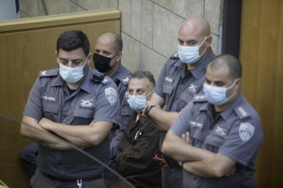 Yakub Kadari is surrounded by guards in a courtroom in Nazareth, Israel, after he and three other Palestinian fugitives were captured on Saturday, Sept. 11, 2021. Israeli police on Saturday said they have arrested four of the six Palestinians who broke out of a maximum-security prison this week — including a famed militant leader whose exploits over the years have made him a well-known figure in Israel. (AP Photo/Sebastian Scheiner)