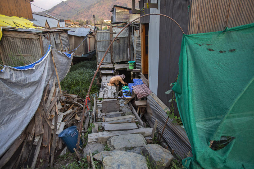 A Kashmiri woman collects water outside their shanty over the Dal Lake in Srinagar, Indian controlled Kashmir, Thursday, Sept. 16, 2021. Weeds, silt and untreated sewage are increasingly choking the sprawling scenic lake, which dominates the city and draws tens of thousands of tourists each year. (AP Photo/Mukhtar Khan)