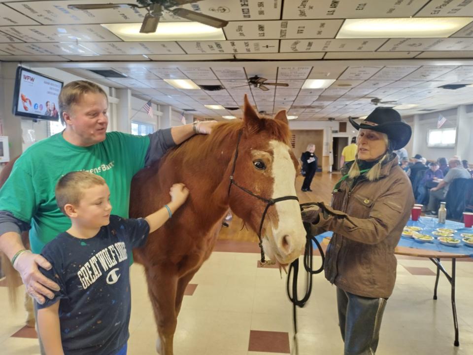 Tom Vekeman, a Citizens Bank volunteer, and 9-year-old Jaxson Atkinson meet one of the Medicine Horse “therapists,” brought into the Tiverton VFW by Carol Ann Silva, right.