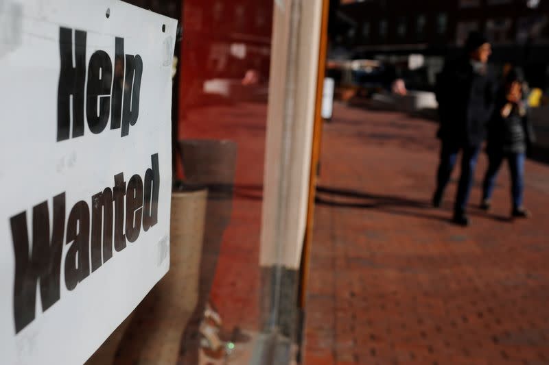 A "Help Wanted" sign sits in the window of a shop in Harvard Square in Cambridge