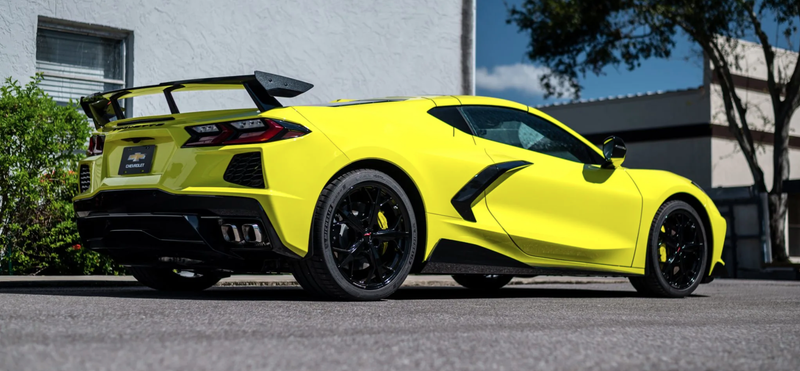 A bright yellow 2021 Corvette Stingray Coupe with black accents, photographed in an office park