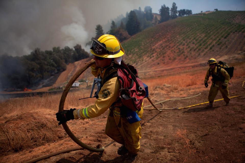 Marin County firefighters haul a hose on a fire line while battling the "Sand Fire" near Plymouth, California