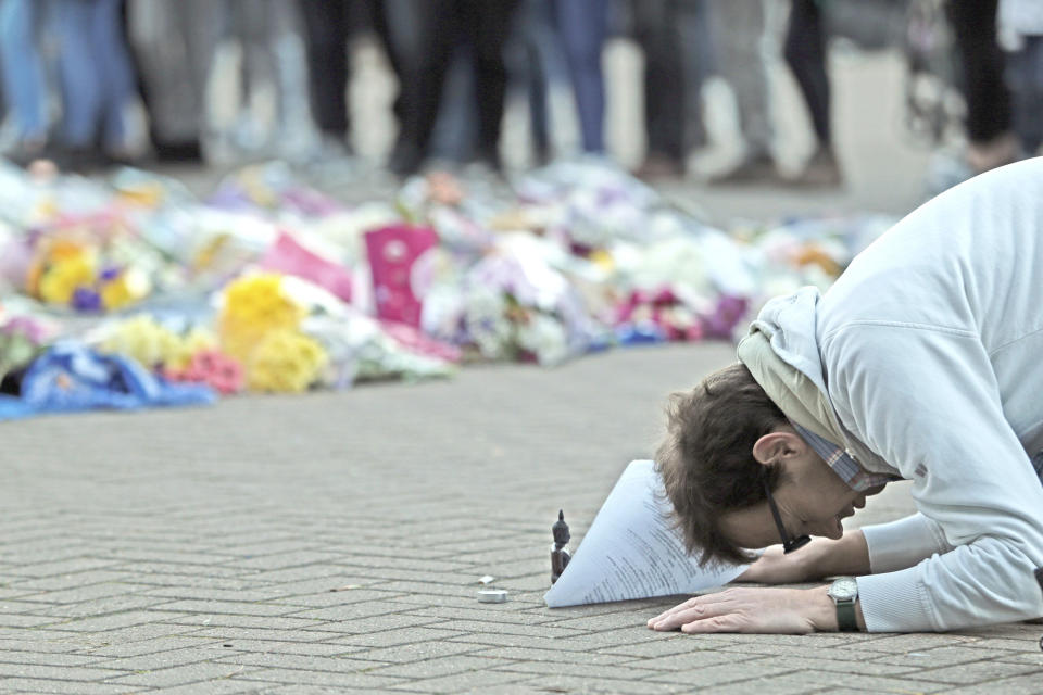 A man prays next to floral tributes outside Leicester City Football Club after a helicopter crashed in flames the day before, in Leicester, England, Sunday, Oct. 28, 2018. A helicopter belonging to Leicester City's owner, Thai billionaire Vichai Srivaddhanaprabha, crashed in flames in a car park next to the soccer club's stadium shortly after it took off from the field following a Premier League game on Saturday night. (Aaron Chown/PA via AP)