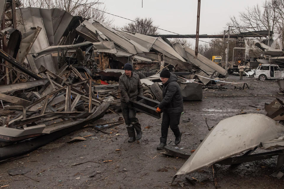 Workers clean debris from the site of a destroyed hangar.  (Roman Pilipey / AFP via Getty Images)