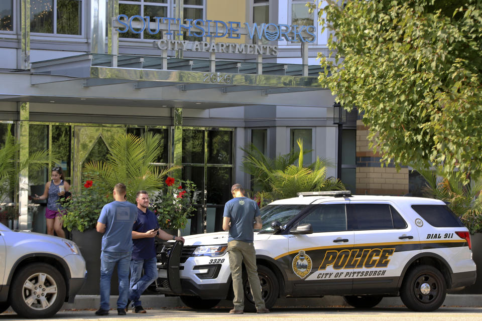 Pittsburgh police investigators gather outside an apartment building on the city's South Side where police say multiple people are dead and others are hospitalized in what they're calling a "medical situation" Sunday, Sept. 22, 2019 in Pittsburgh. Police said Sunday that all of the victims were wearing orange paper bands on their wrists. Authorities are asking the public for information on a party or event in which guests were given orange wrist bands. Police say they've identified two venues that were using orange wrist bands Saturday night. (AP Photo/Gene J. Puskar)