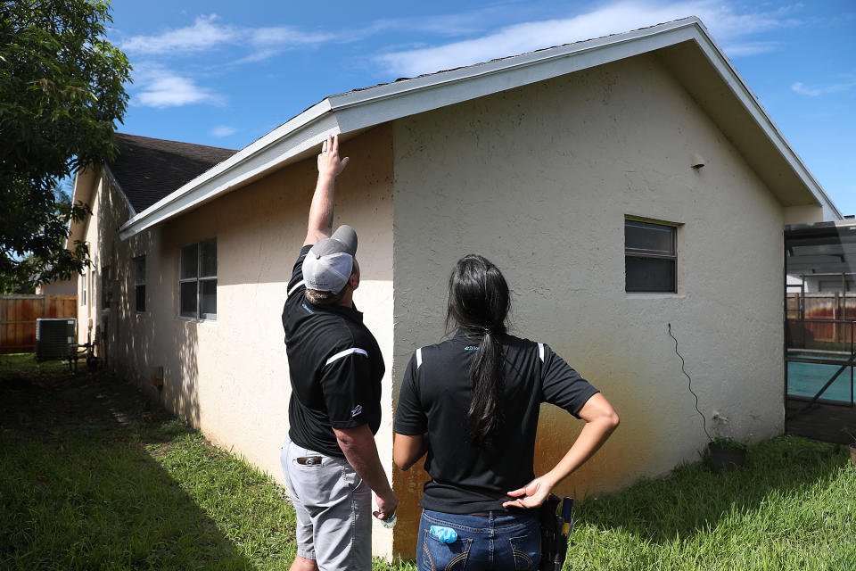 (L-R) J Myers, Zillow Offers National Renovation Manager and Claudia Teyssandier, Zillow Offers Renovation Estimator, evaluate a home for a possible purchase by Zillow in Lauderhill, Florida. (Credit: Joe Raedle/Getty Images)