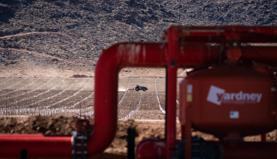 A tractor working in a field is framed by groundwater filters at Stockton Hill Farms, March 8, 2022, north of Kingman, Ariz.