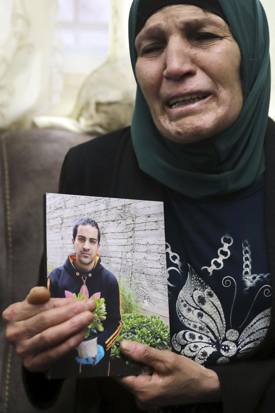 Rana, mother of Iyad Halak, 32, holds his photo at their home in East Jerusalem's Wadi Joz, Saturday, May 30, 2020. Israeli police shot dead a Palestinian near Jerusalem's Old City who they had suspected was carrying a weapon but turned out to be unarmed. A relative said Halak was mentally disabled and was heading to a nearby school for people with special needs. (AP Photo/Mahmoud Illean)