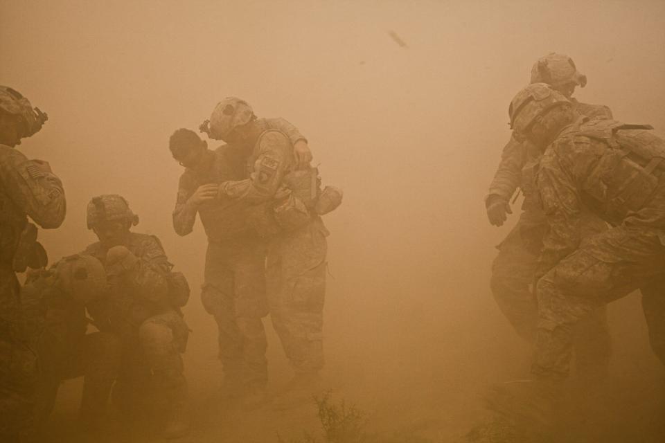 U.S. infantry soldiers shield themselves from dust and debris as a medevac helicopter lands to evacuate soldiers injured from two IED attacks during "Operation Clarksville" in Kandahar Province, Afghanistan. Oct. 9, 2010.