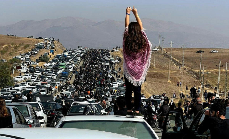 A woman stands on top of a car (via Twitter)