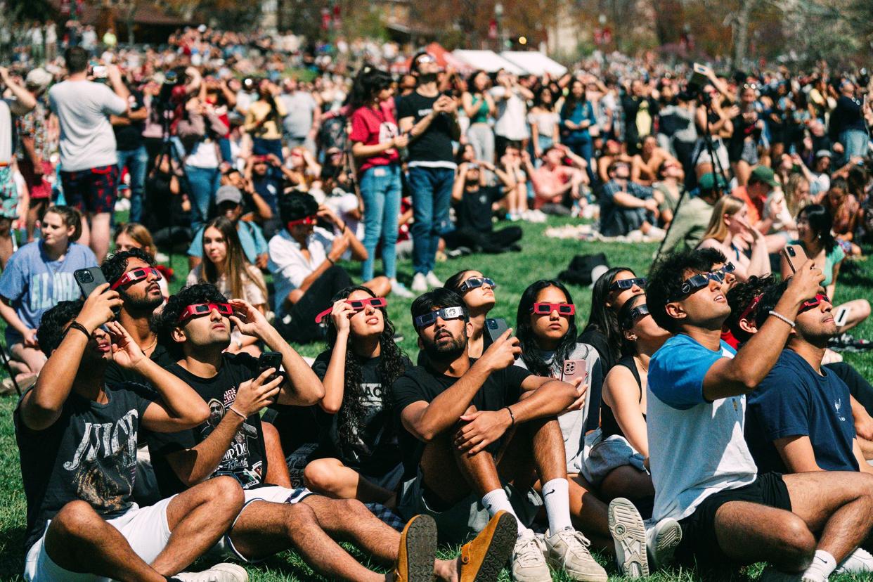 A group looks at the sun with their eclipse glasses in Dunn Meadow during Eclipse Day on Monday, April 8th, 2024