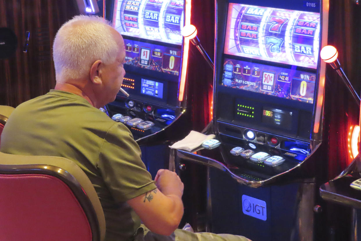 A gambler smokes while playing a slot machine at the Hard Rock casino in Atlantic City, N.J., on Aug. 8, 2022. (AP Photo/Wayne Parry)