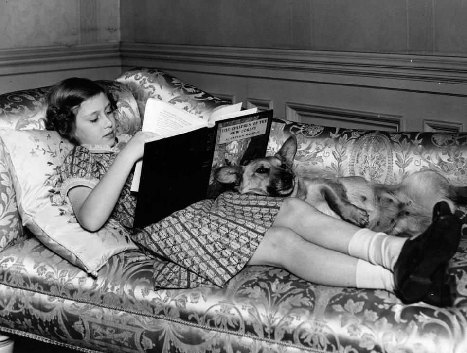 Princess Margaret reading on the sofa at Windsor Castle with the family corgi, Jane, in 1940