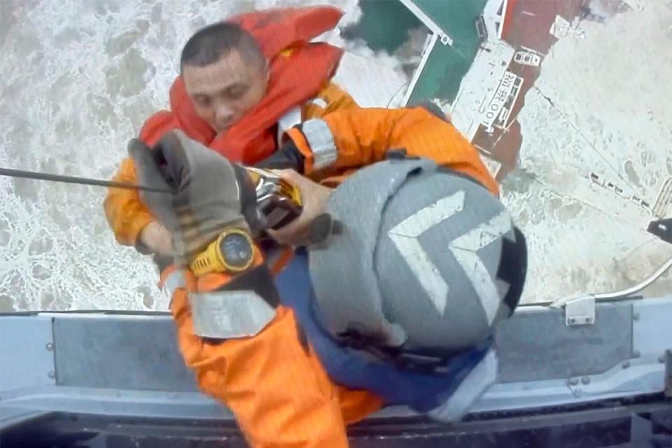 In this image released by Hong Kong Government Flying Service, helicopter crew members winch up a man from a sinking ship in the South China Sea, 300 kilometers (186 miles) south of Hong Kong, Saturday, July 2, 2022, as Typhoon Chaba was moving in the area. The industrial support ship operating in the South China Sea has sunk with the possible loss of more than two dozen crew members, rescue services in Hong Kong said Saturday.