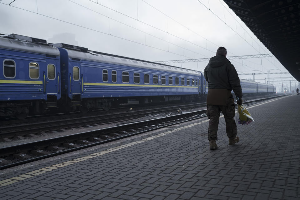 El soldado ucraniano Vasyl Khomko, de 42 años, sostiene un ramo de flores mientras espera la llegada de su hija y su esposa a la estación ferroviaria, el sábado 31 de diciembre de 2022, en Kiev, Ucrania. (AP Foto/Roman Hrytsyna)