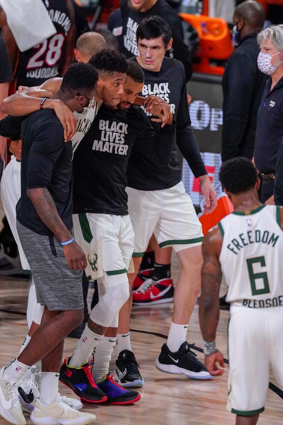 Bucks star Giannis Antetokounmpo is helped off the court after re-injuring his right ankle during the first half against Miami.