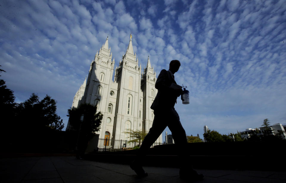 FILE - In this Sept. 14, 2016, file photo, a man walks past the Salt Lake Temple, a temple of The Church of Jesus Christ of Latter-day Saints, at Temple Square in Salt Lake City. Parents of Mormon missionaries will be able to hear their children's voices a lot more often under new rules announced Friday, Feb. 15, 2019, that allow the proselytizing youngsters to call home every week instead of only twice a year. (AP Photo/Rick Bowmer, File)