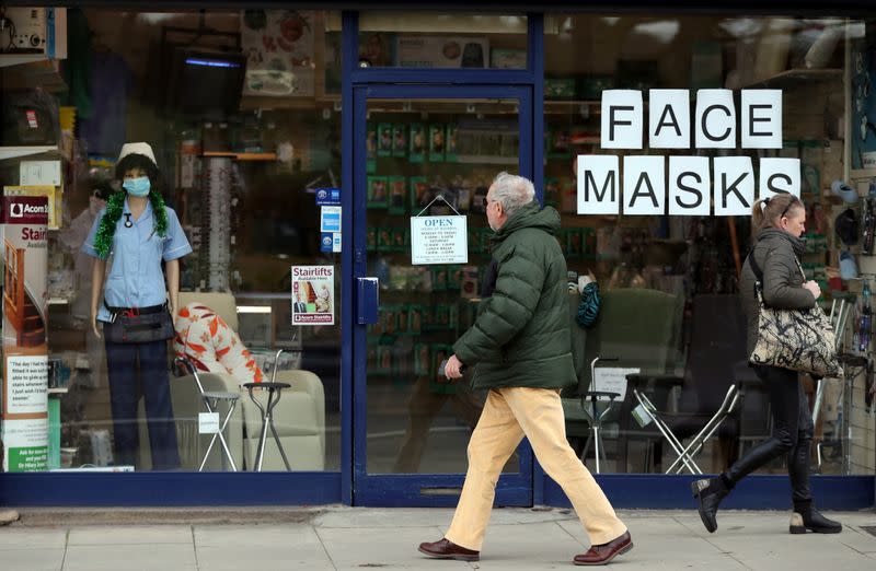 People walk past the window of a medical equipment supply store advertising the sale of protective masks in south London