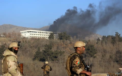 Afghan security personnel stand guard as black smoke rises from the Intercontinental Hotel after an attack in Kabul - Credit: AP Photo/Rahmat Gul