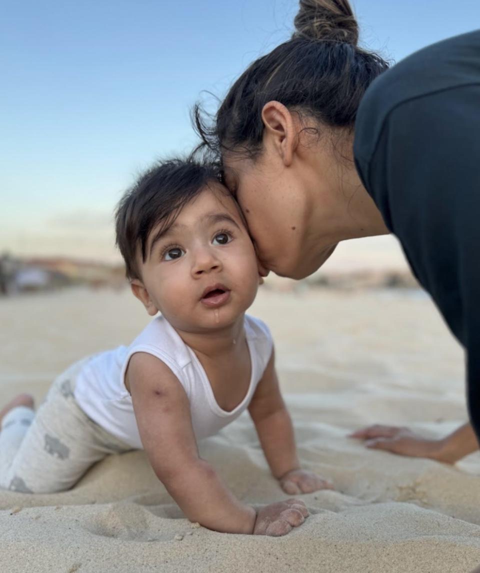 Baby crawling in the sand with his mother