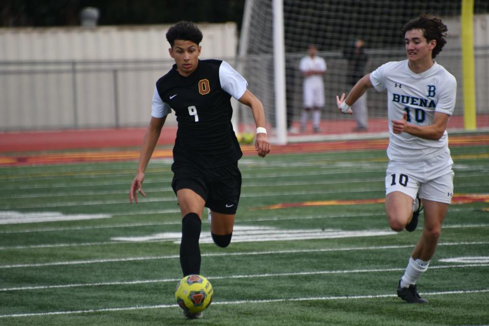 Oxnard defender Miguel Cabrera is chased by Buena forward Ashton Reynolds-King in a Channel League boys soccer match on Dec. 17.